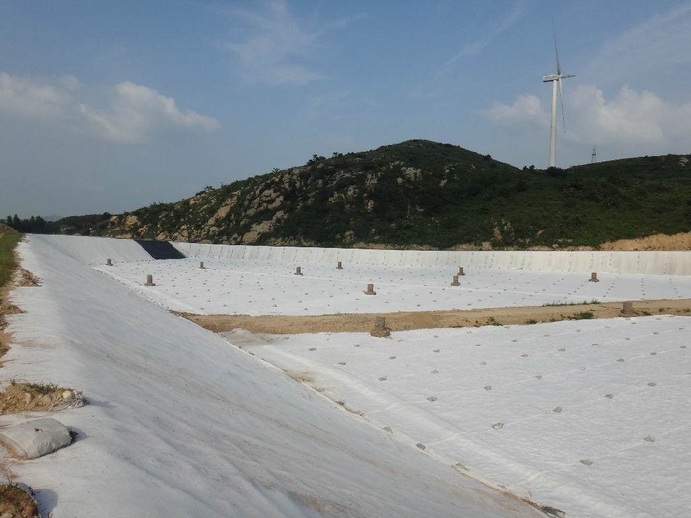 Why is asphalt sprayed before laying geotextile fabric?